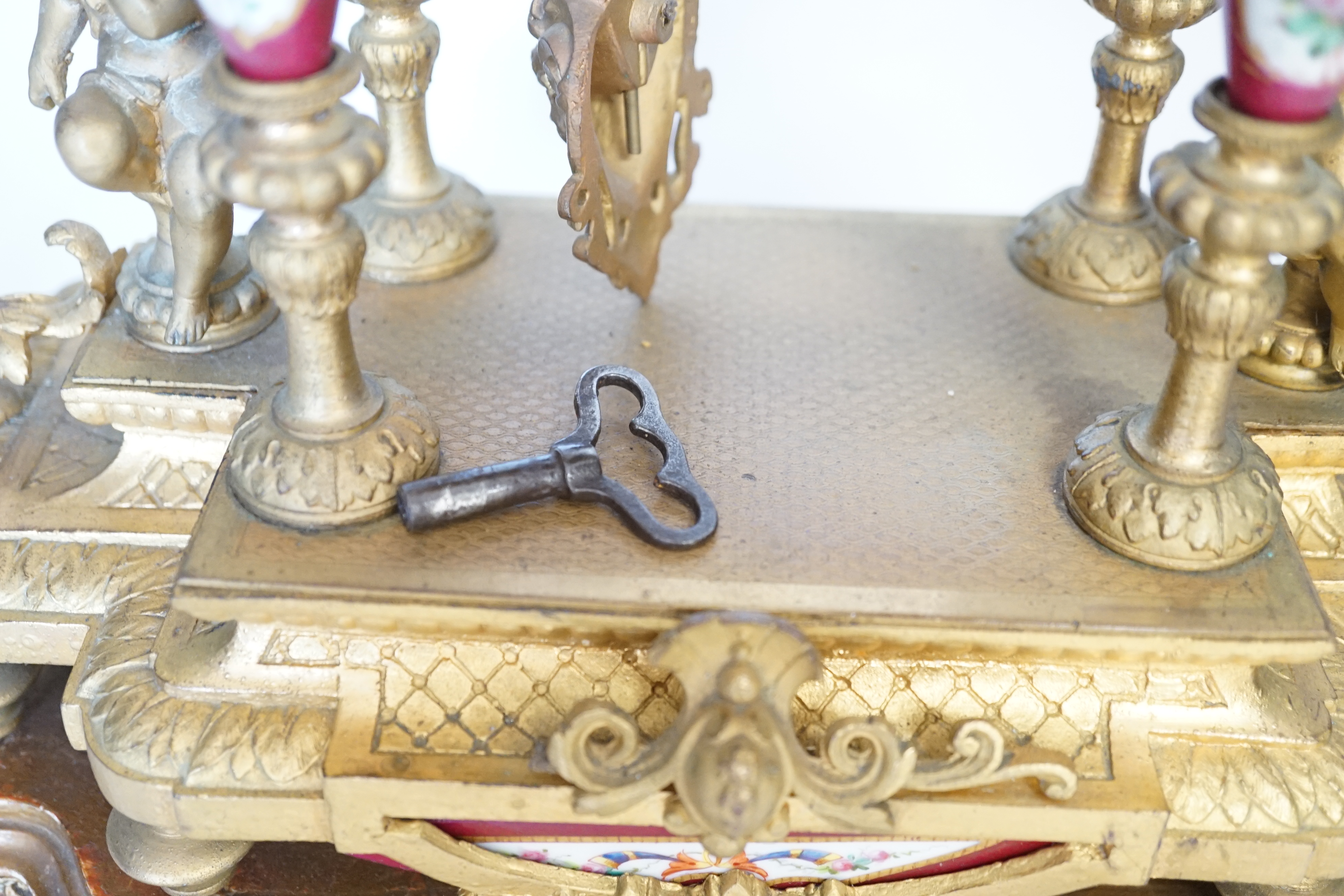 A late 19th century gilt metal and porcelain mounted mantel clock with associated stand, key and pendulum, 46cm. Condition - good to fair, not tested